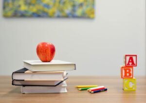 apple and books on classroom desk  